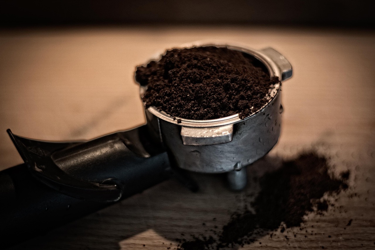 Fondi di caffè sparsi intorno a piante in vaso, evidenziando l'uso come fertilizzante naturale.