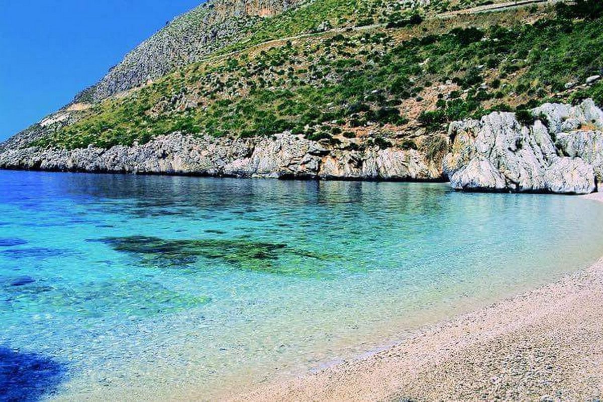 Spiaggia di Cala Domestica con miniere abbandonate sullo sfondo, tipico paesaggio del Sulcis sardo.