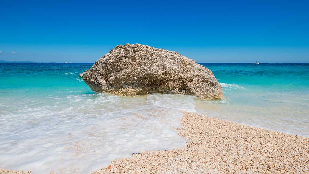 Cala Mariolu, spiaggia sarda con ciottoli bianchi simili a uova, circondata da acque cristalline.